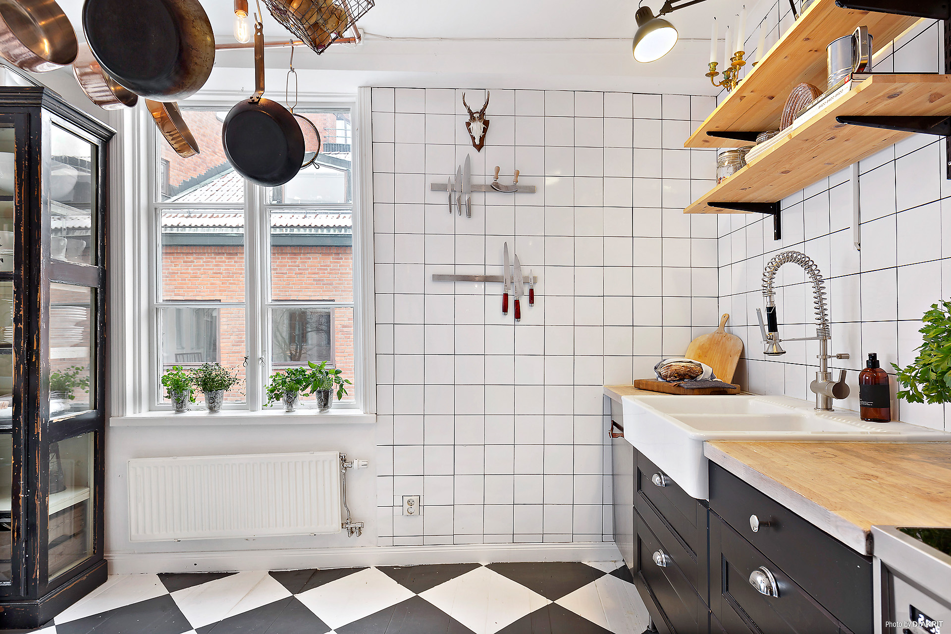 厨房选用黑白地砖铺设地面，这就给该区域定下了黑白的基调。墙面是小方砖铺墙。银色的冰箱与黑白对比起来显得熠熠生辉。