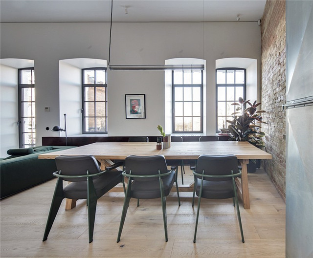 黑色皮革与墨绿色金属搭配的餐椅，与客厅的沙发互相呼应。多处的绿植点缀，让风格混搭显得十分自然。