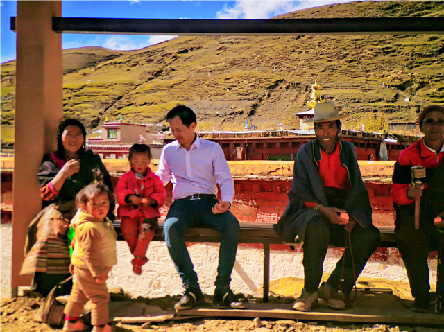 8卢景尧在四川甘孜藏族自治州理塘县高城镇的长青春科尔寺前，带了一些水果给与当地村民互动.jpg